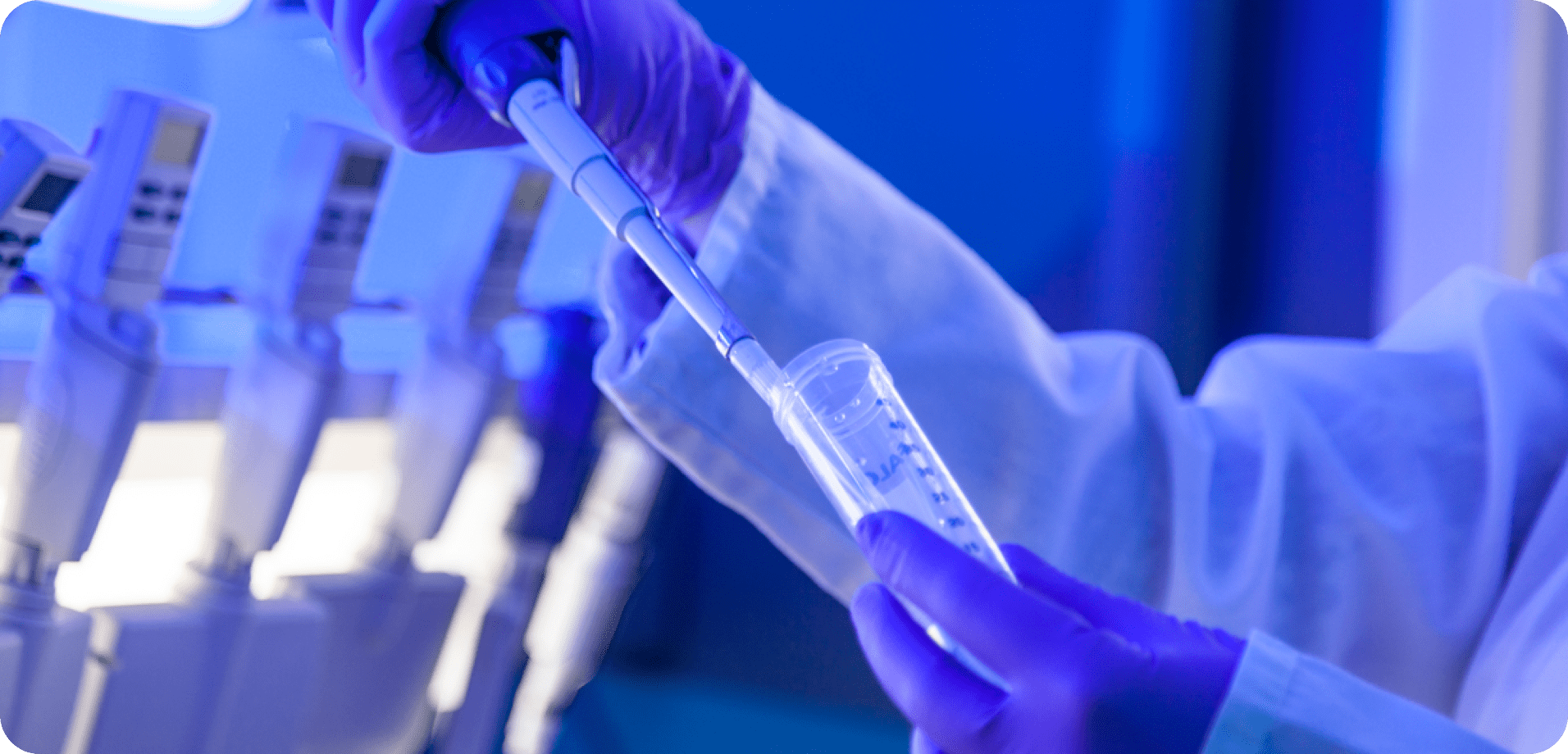 Laboratory close-up of gloved hands using a pipette with a test tube under blue lighting